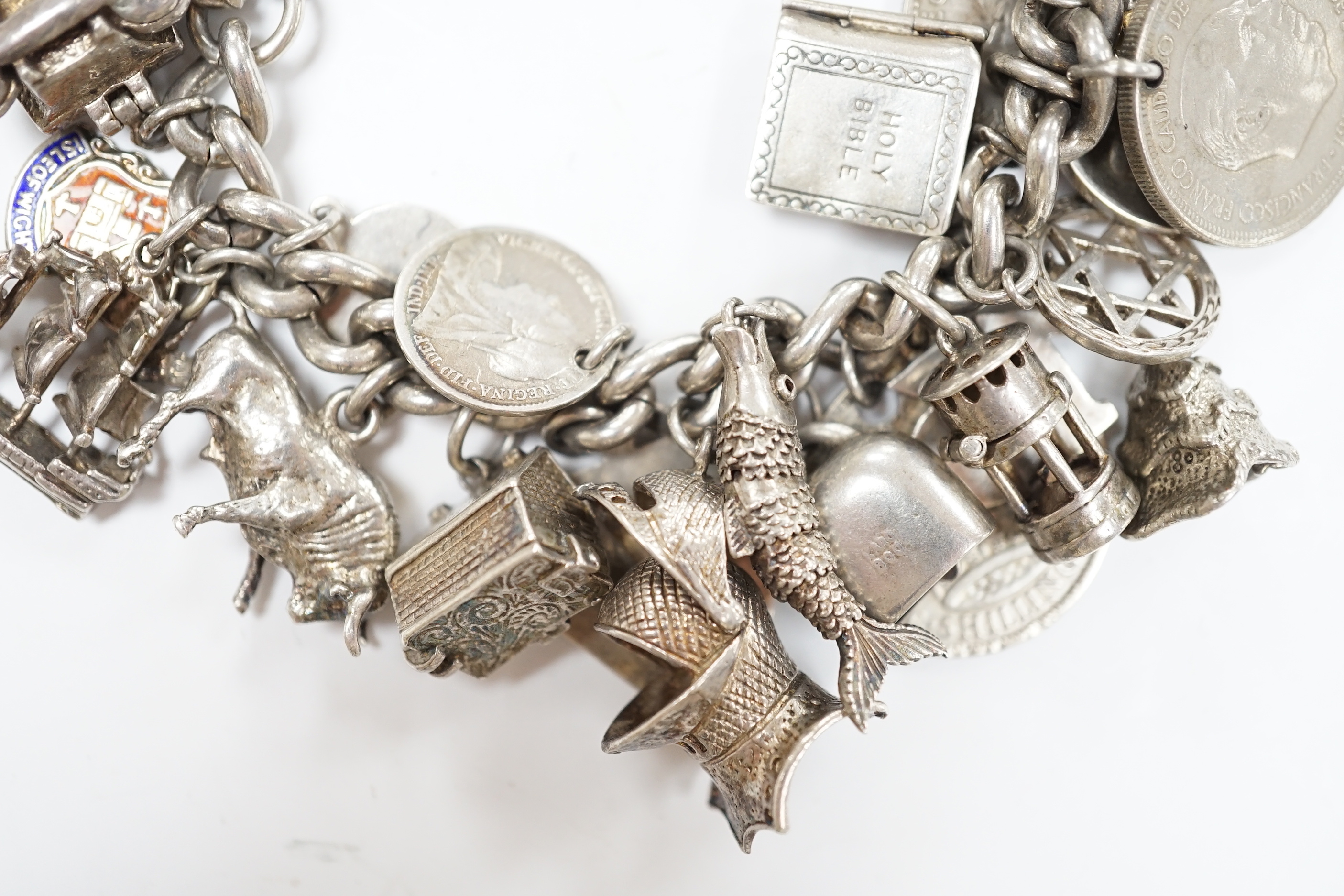 A silver charm bracelet, hung with assorted mainly white metal charms including tankard and Knight's helmet, two 'melted' ingots and a silver medallion.